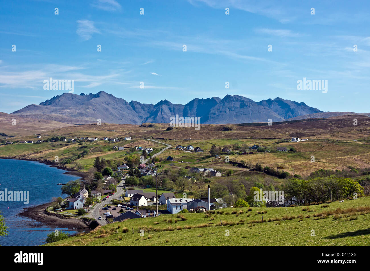 View from above Skye village Carbost towards the Cuillin Hills with Talisker Whisky distillery in the foreground. Stock Photo