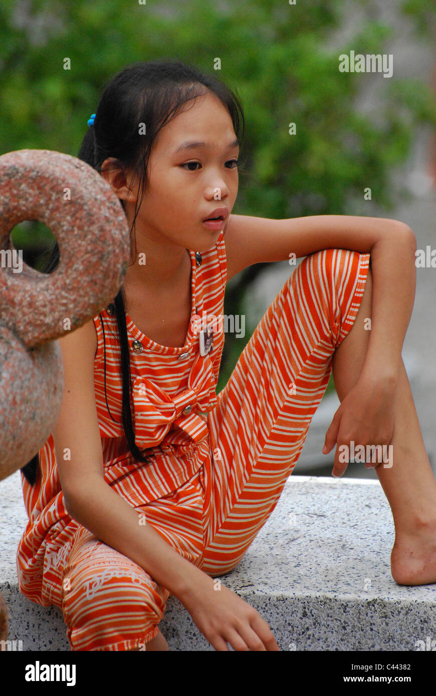 Young Vietnamese girl sitting on a wall in Hanoi, Vietnam Stock Photo