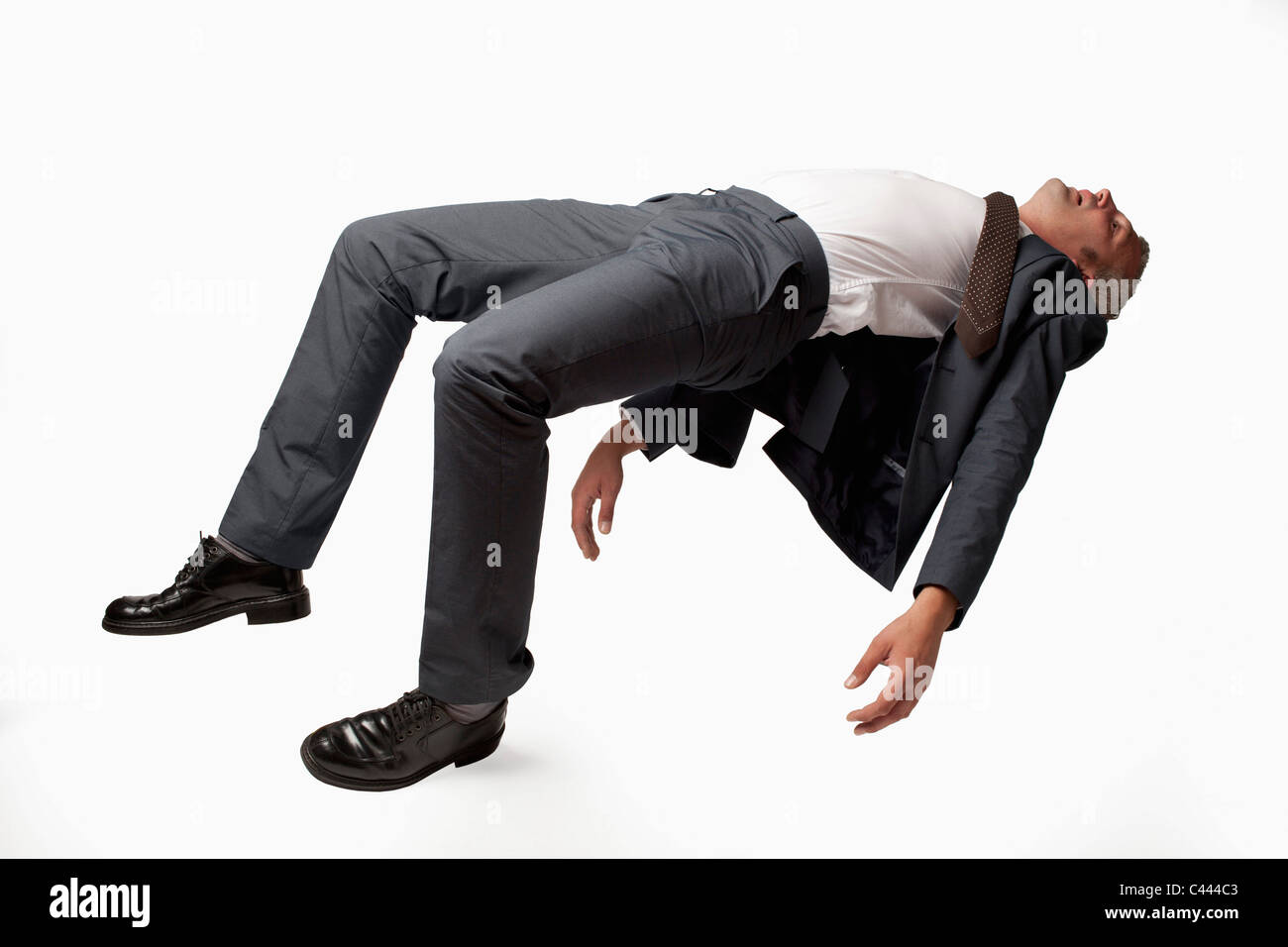 A sleeping businessman in mid-air, studio shot Stock Photo