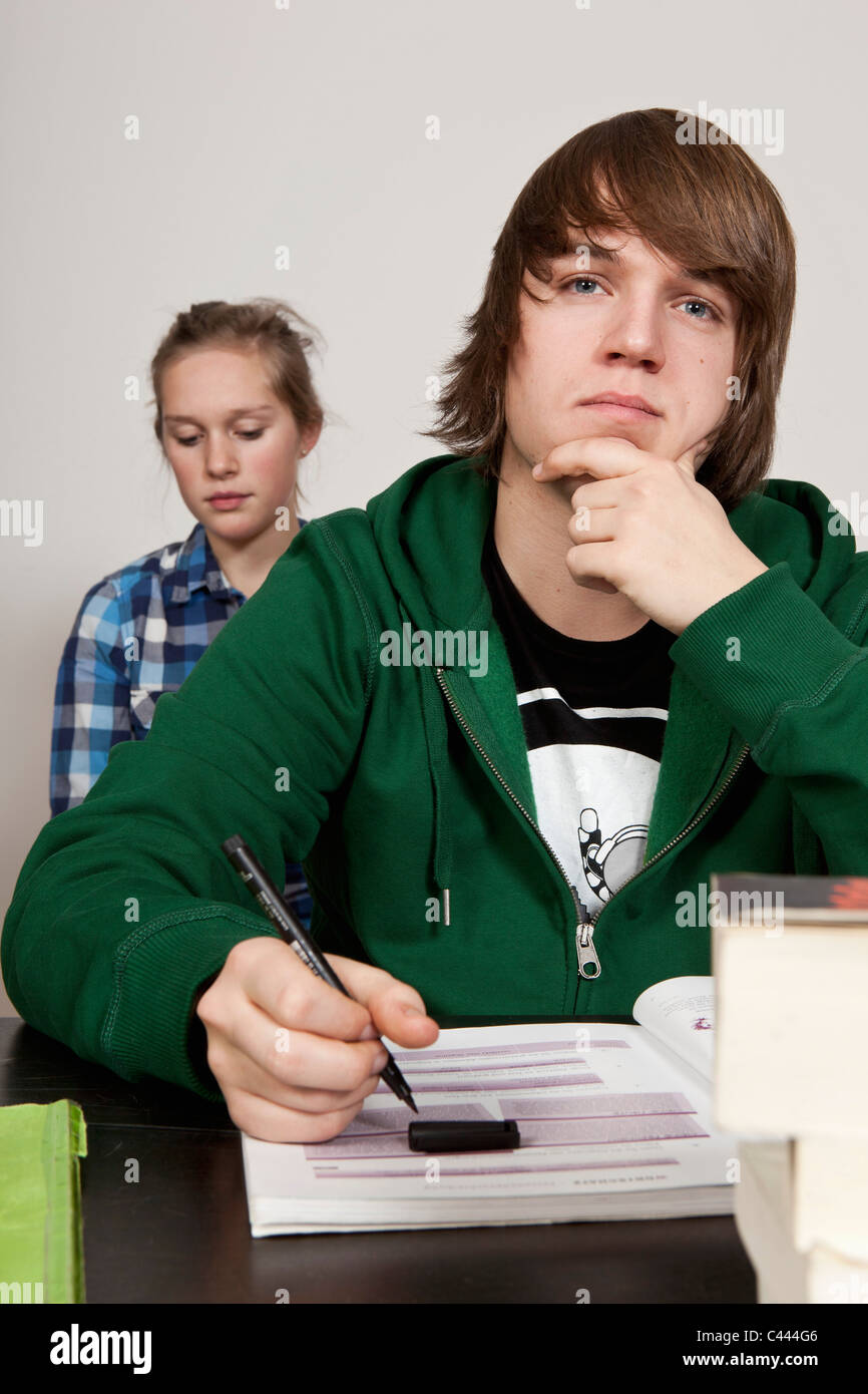 A teenage boy thinking in a classroom, girl in background Stock Photo