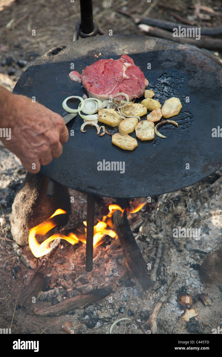 Detail of a man cooking food over a campfire Stock Photo