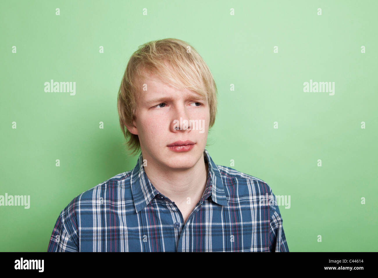 A teenage boy looking off to the side with suspicion, portrait, studio shot Stock Photo