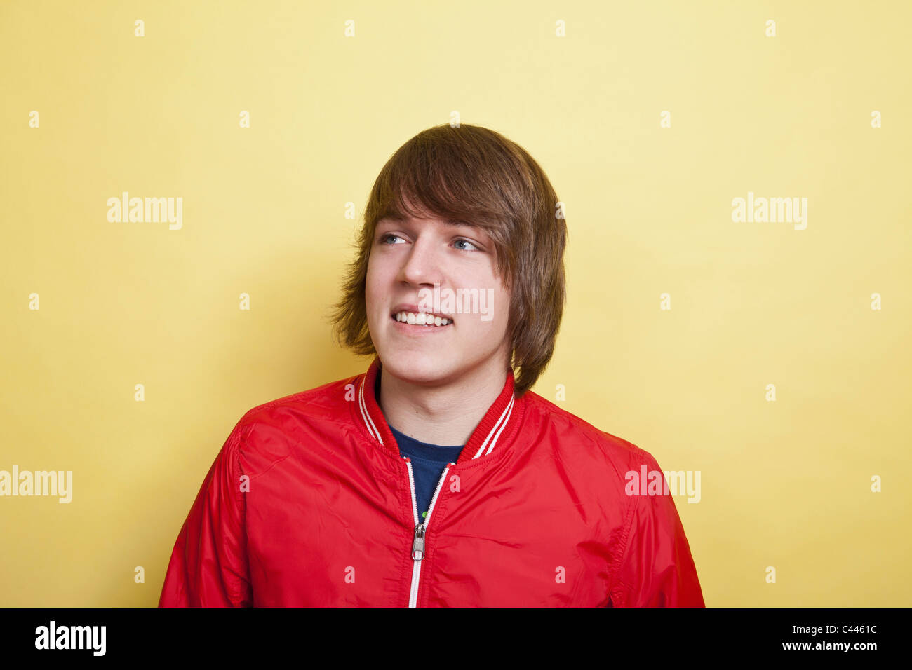 A teenage boy looking off to the side and laughing, portrait, studio shot Stock Photo