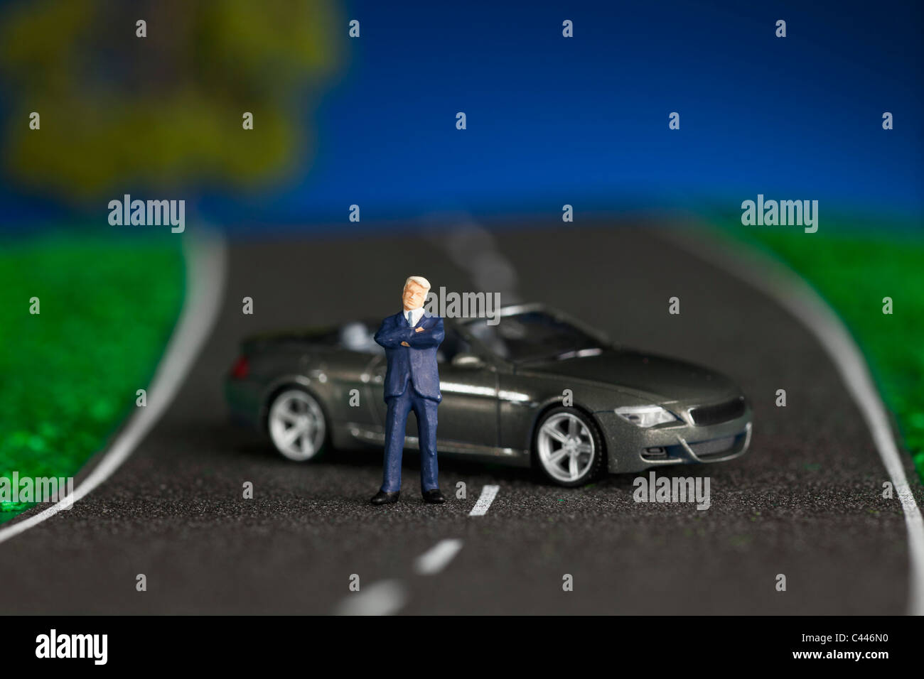 A miniature businessman figurine and miniature sports car Stock Photo