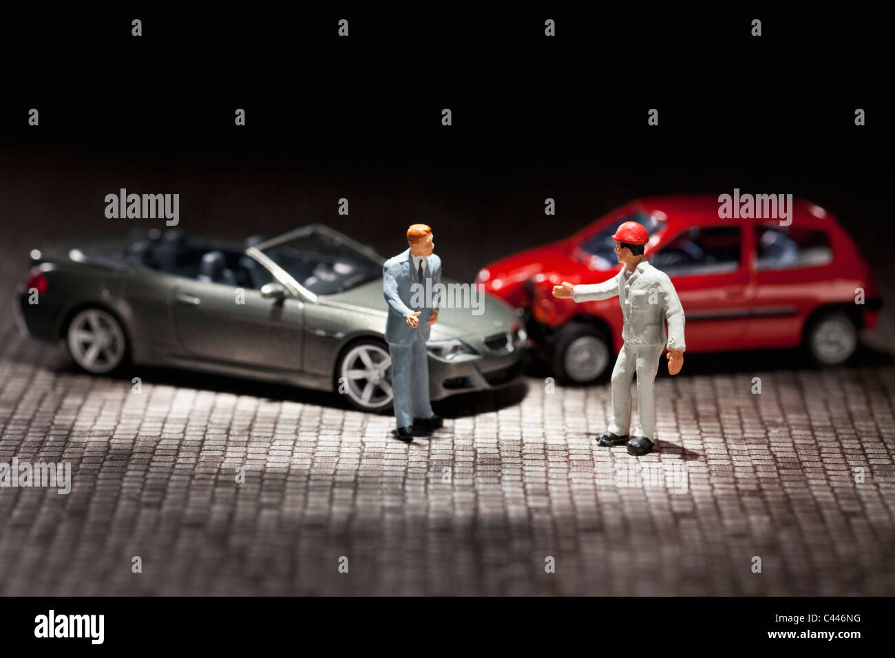 Two miniature figurine men arguing over their miniature crashed cars Stock Photo