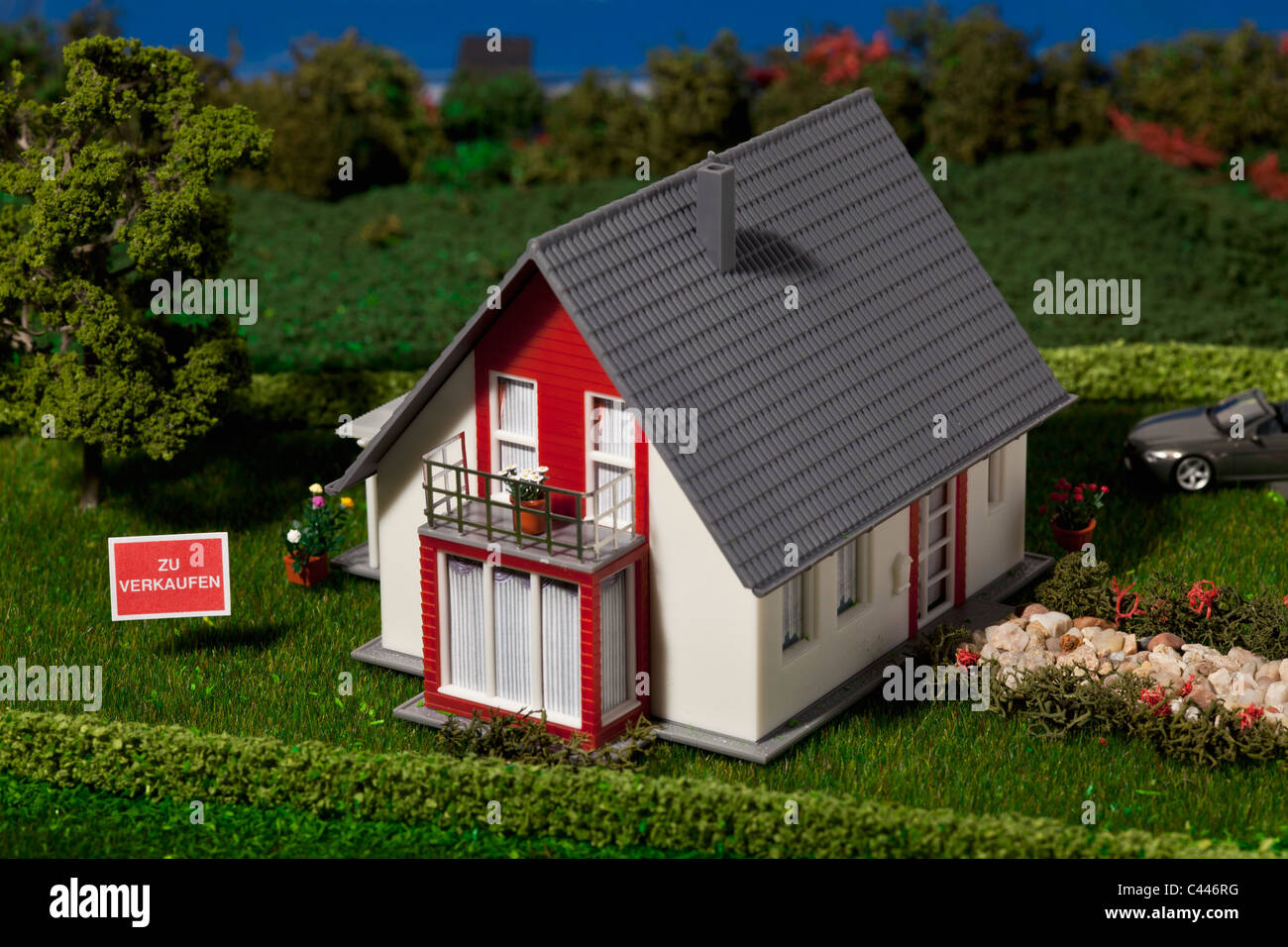 A diorama of a miniature house with a  ZU VERKAUFEN (for sale in German) sign Stock Photo