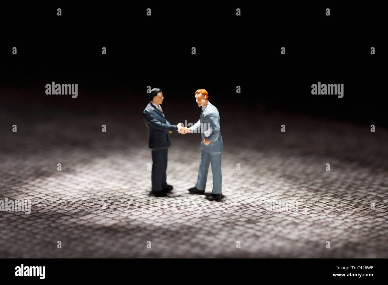 Two miniature businessmen figurines shaking hands Stock Photo
