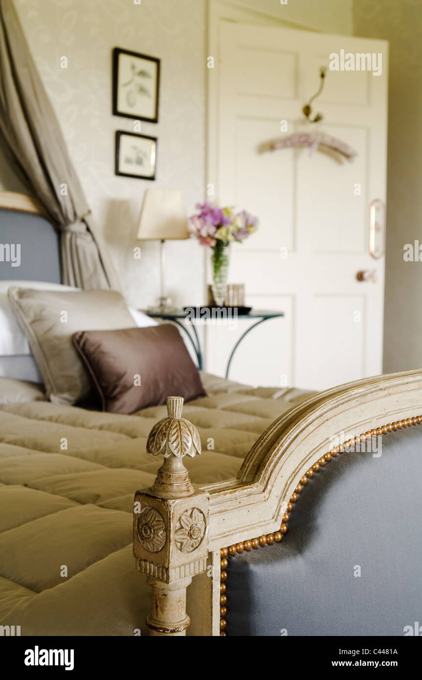 Detail of padded foot board of antique bed with eiderdown quilt and silk cushions Stock Photo