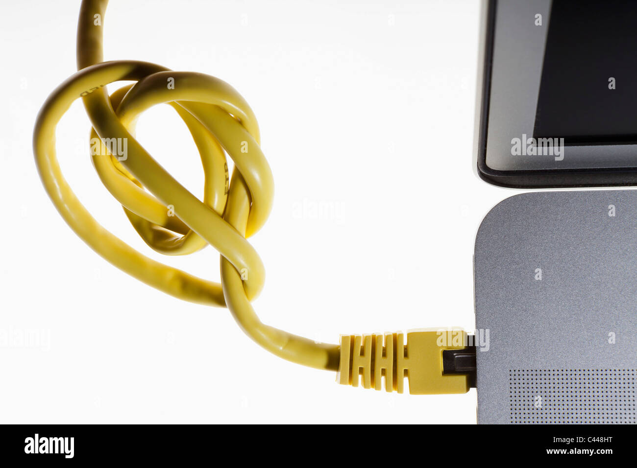 A tangled network cord plugged into a laptop Stock Photo