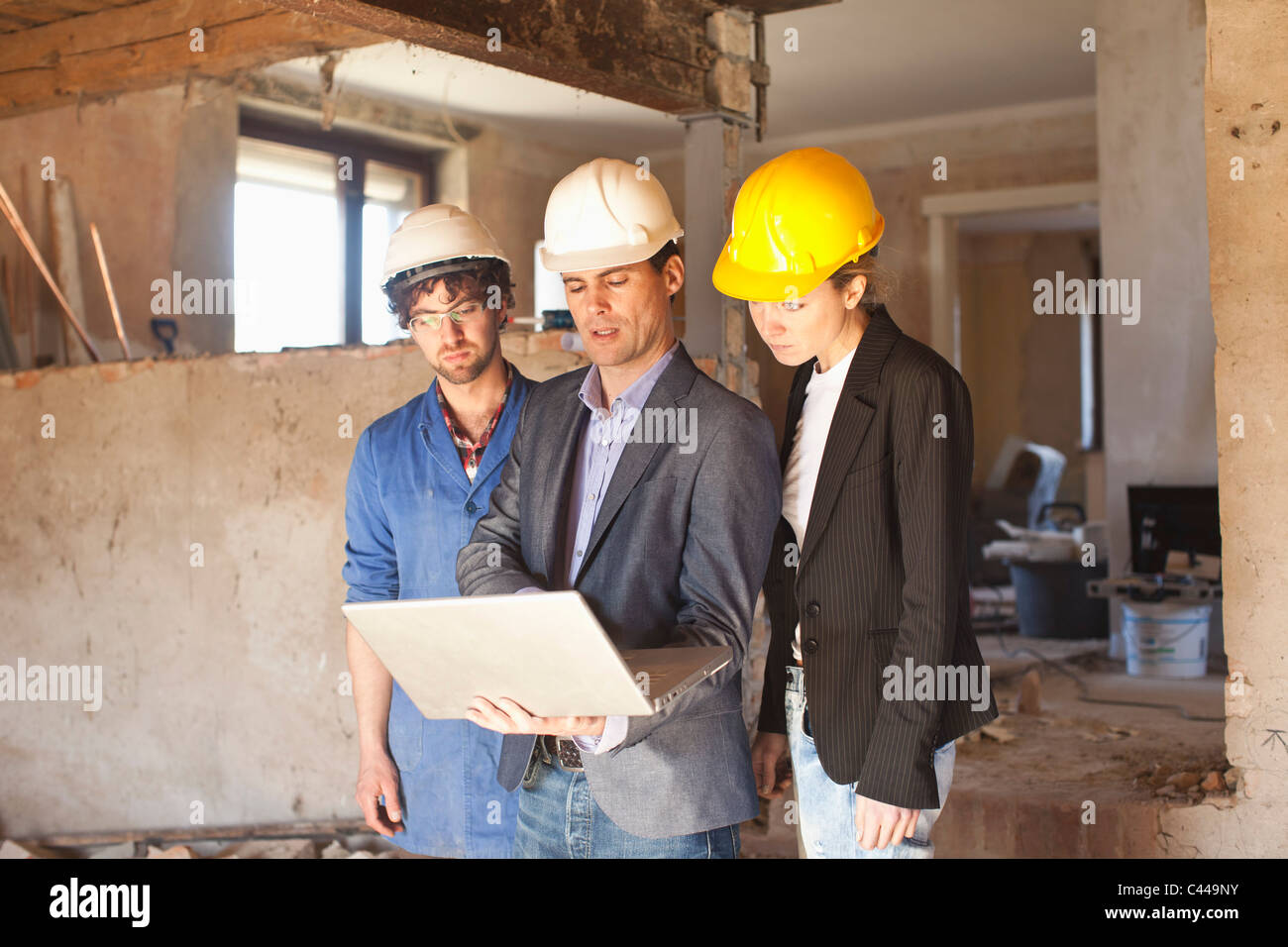 A building contractor and architects looking at a laptop at a building site Stock Photo