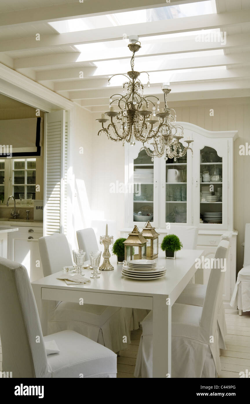 White Dining Table With Chairs Lanterns And Chandeliers And Cabinet Stock Photo Alamy