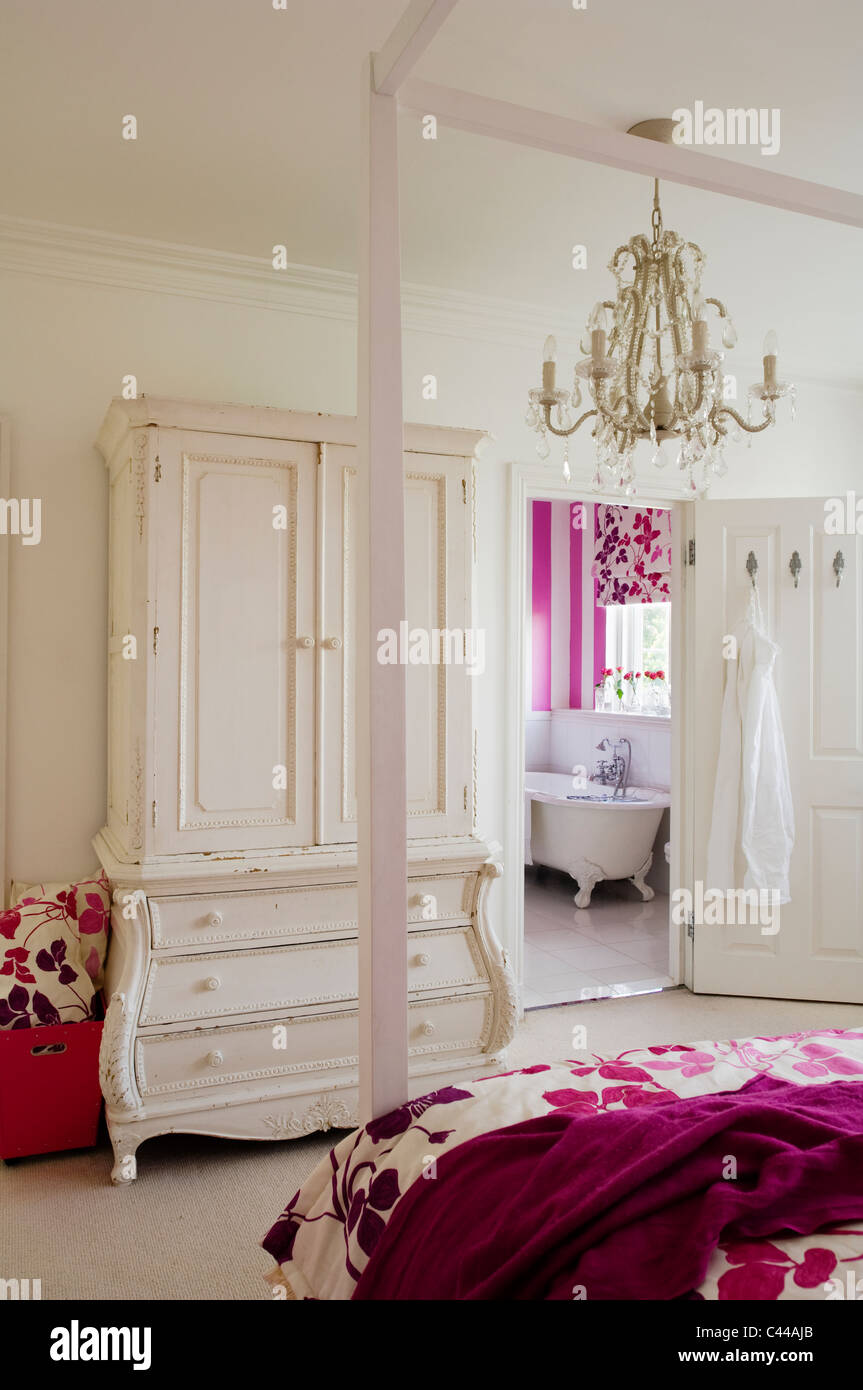 Fourposter bed in bedroom with white wardrobe with drawers, chandelier and en suite Stock Photo