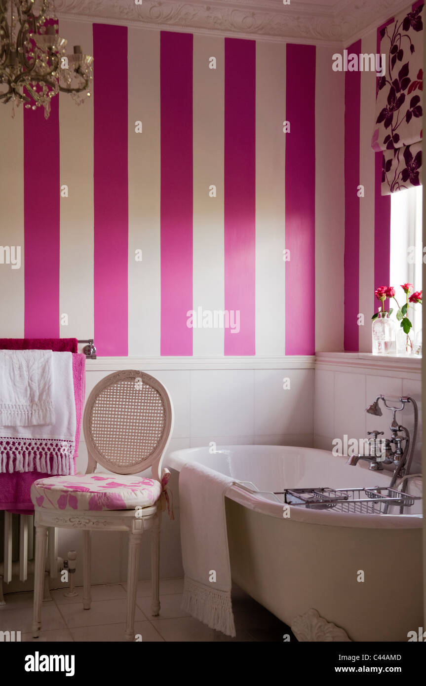 Freestanding bath tub in bathroom with striped wallpaper and floral
