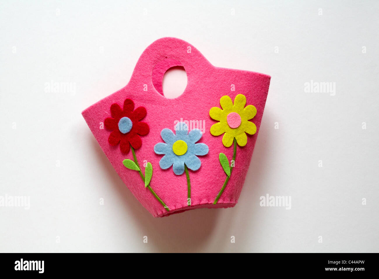 childs pink felt bag with three brightly coloured daisies on it isolated on white background - ready for Easter Stock Photo