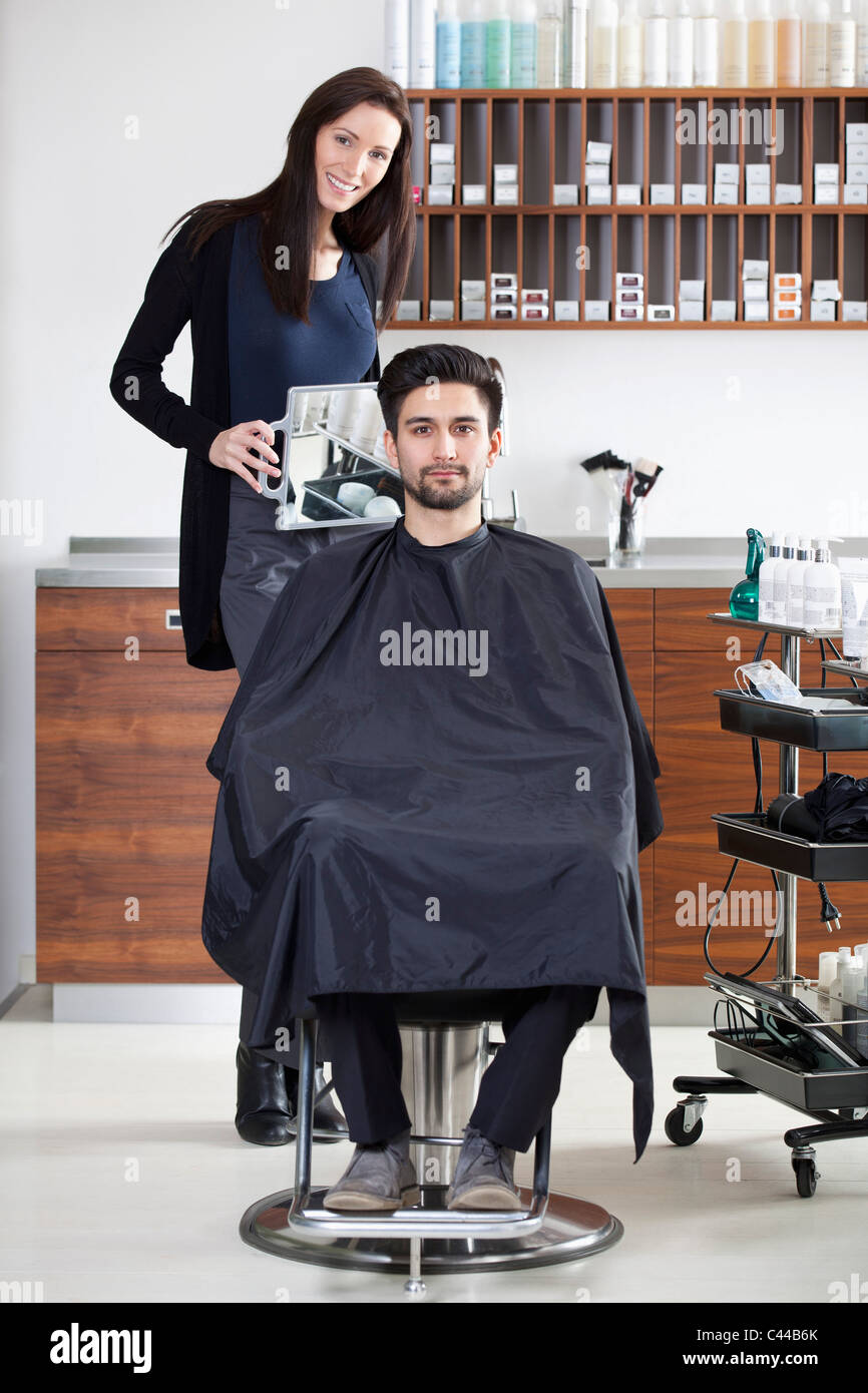 A hairdresser holding a mirror up for customer Stock Photo Alamy