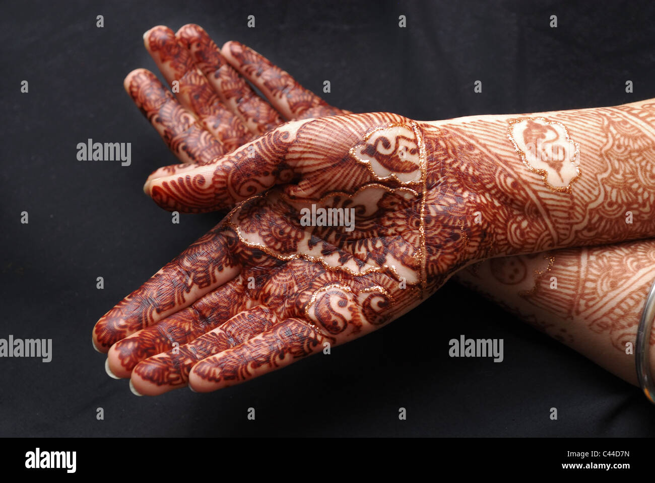 Henna covered hands, photographed on black background to show the richness of the colour Stock Photo