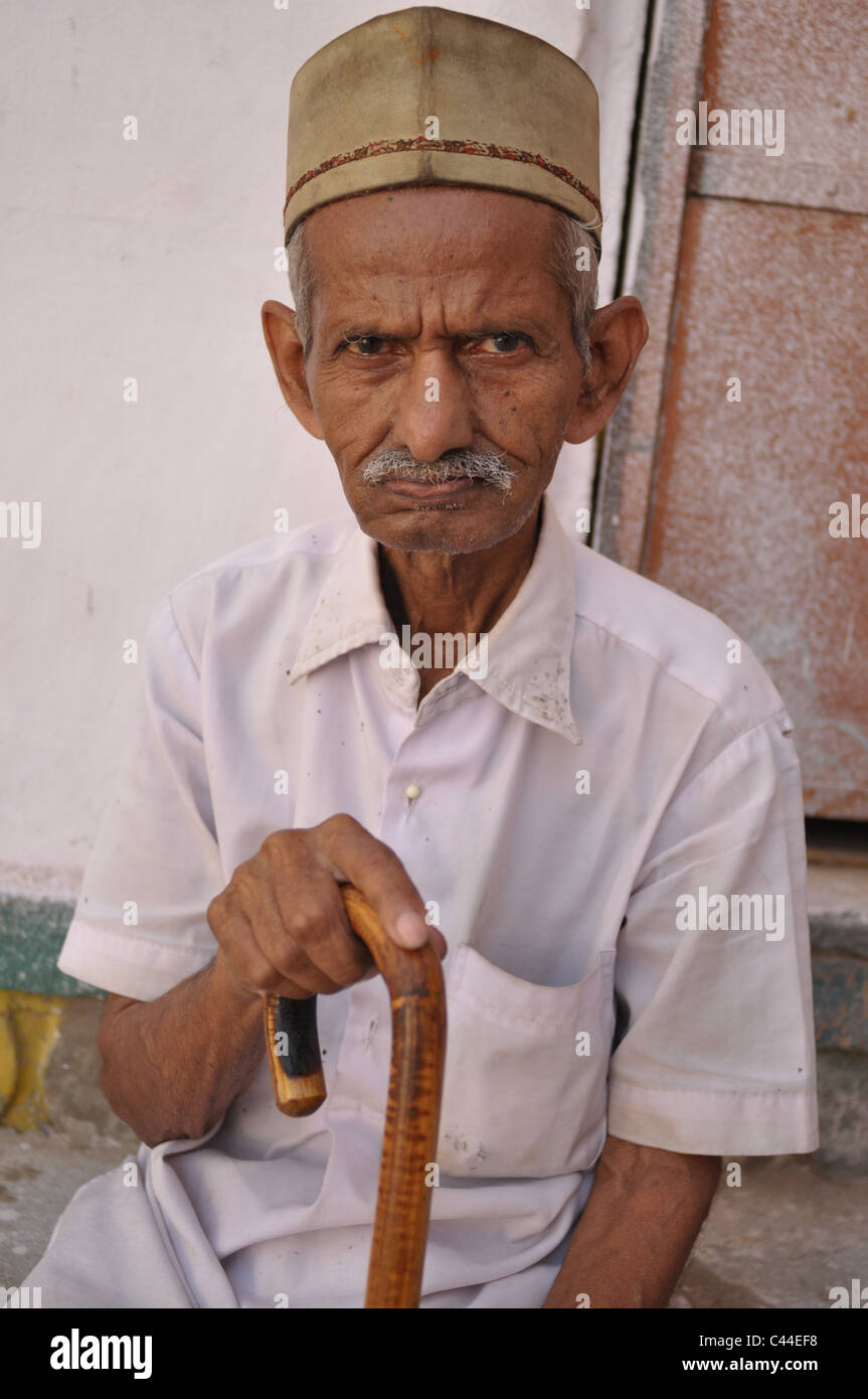 An Old man resting with his walking stick in hand. Stock Photo