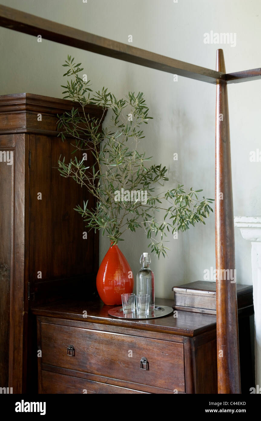 Olive branch in retro style orange vase on antique wooden chest of drawers Stock Photo