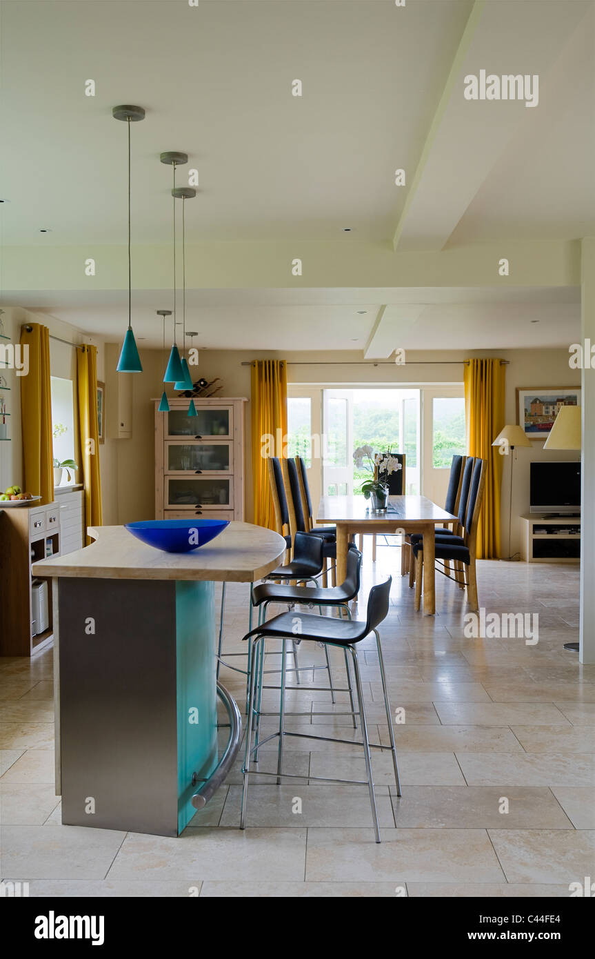 Open plan kitchen with barstools, turquoise pendant lights and french windows Stock Photo