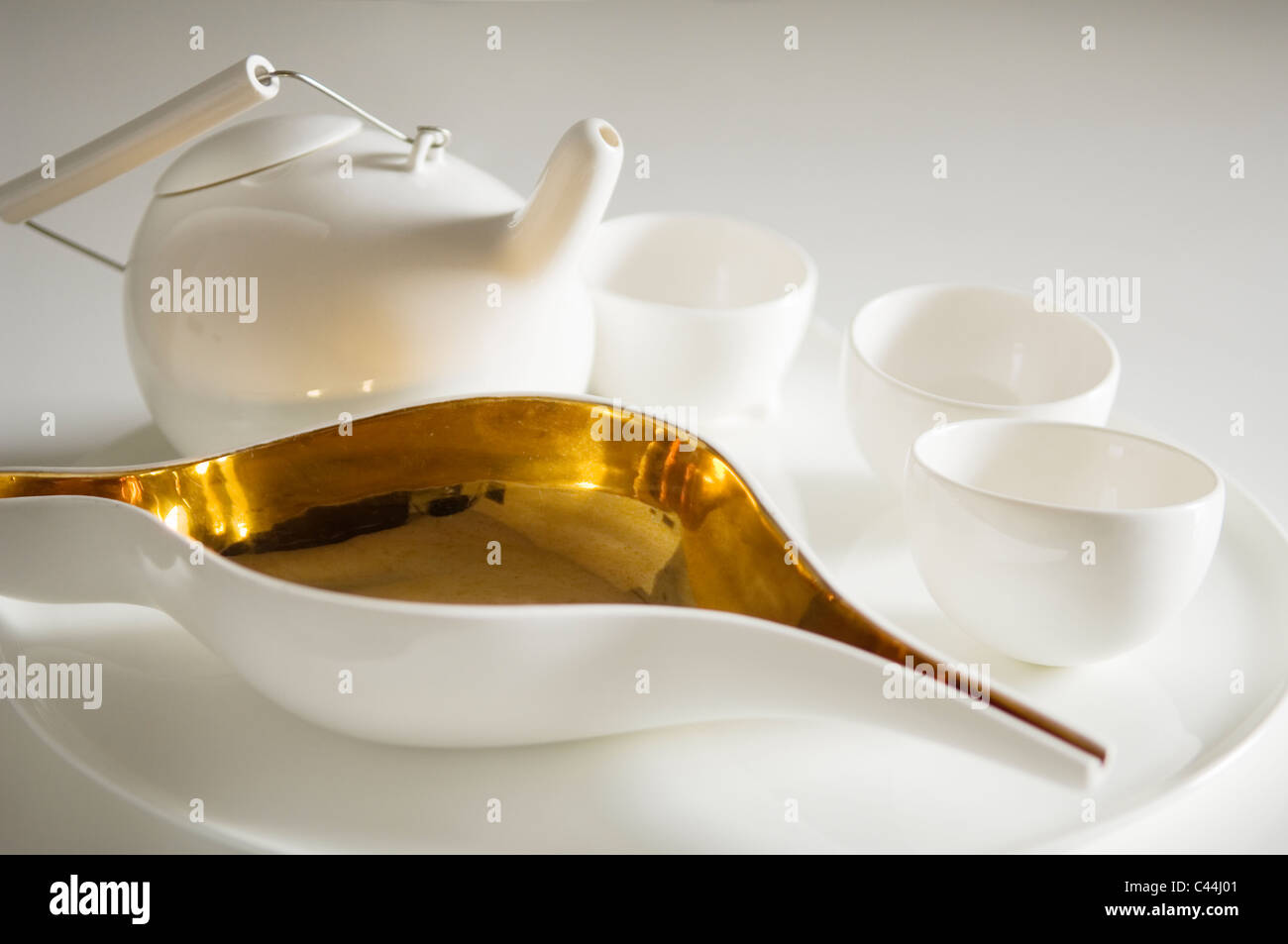 Modern white tea set with pot, cups and milk jug with gold coloured inlay Stock Photo