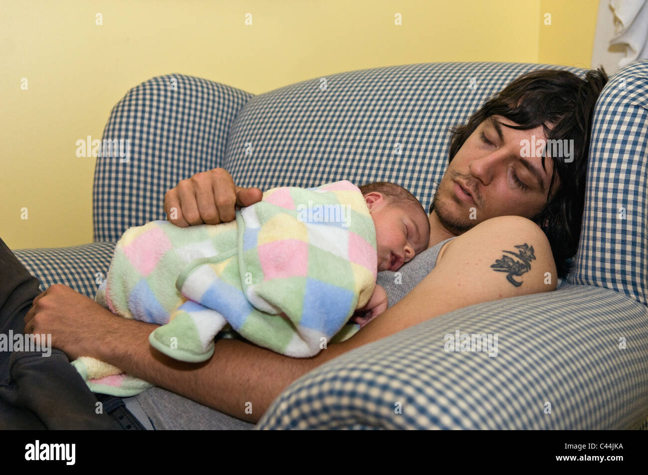 New Father and His One Week Old Baby Boy Asleep on Chair Stock Photo