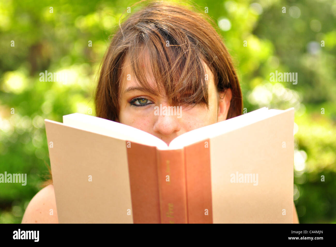 A young woman is reading a book outdoors Stock Photo