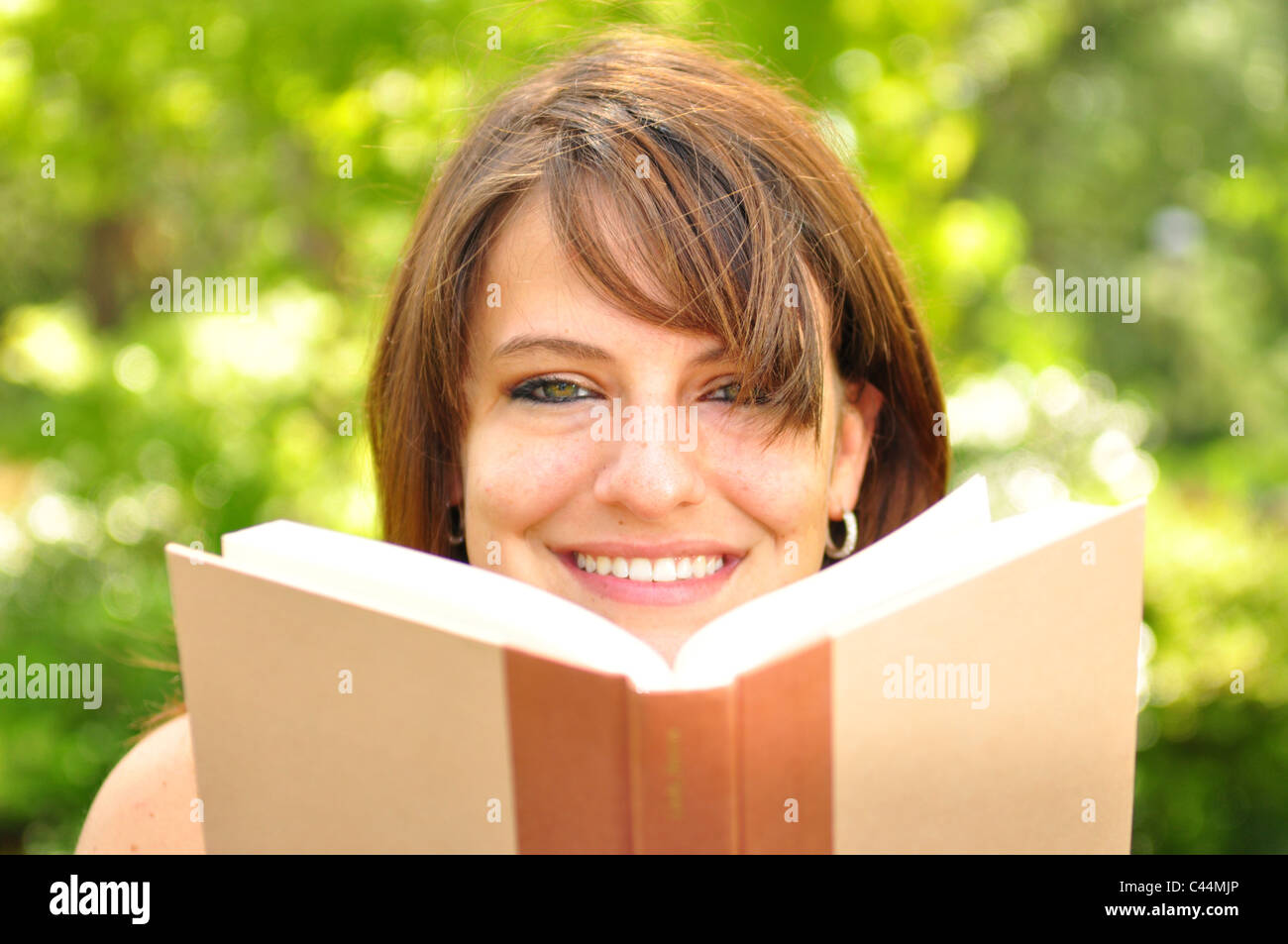 A young woman reading a book outdoors Stock Photo