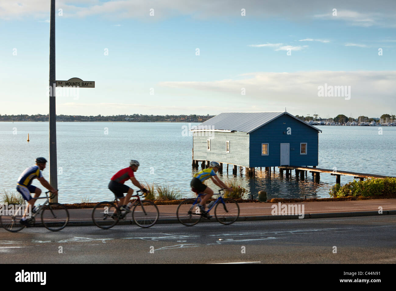 Cyclist riding along Swan River with Crawley Edge Boatshed in