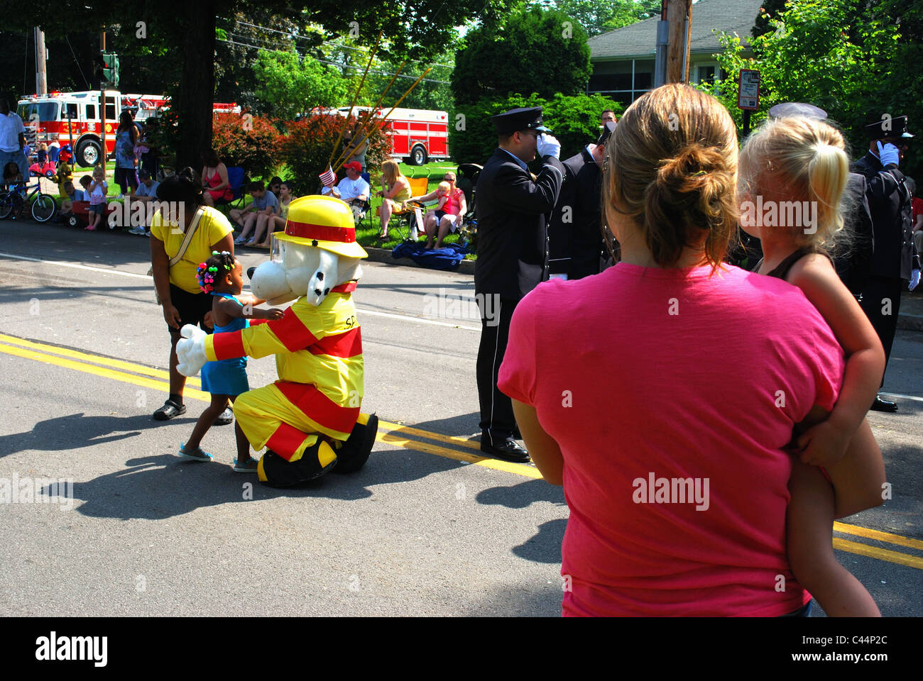 Fireman's mascot hugs child at parade. Stock Photo