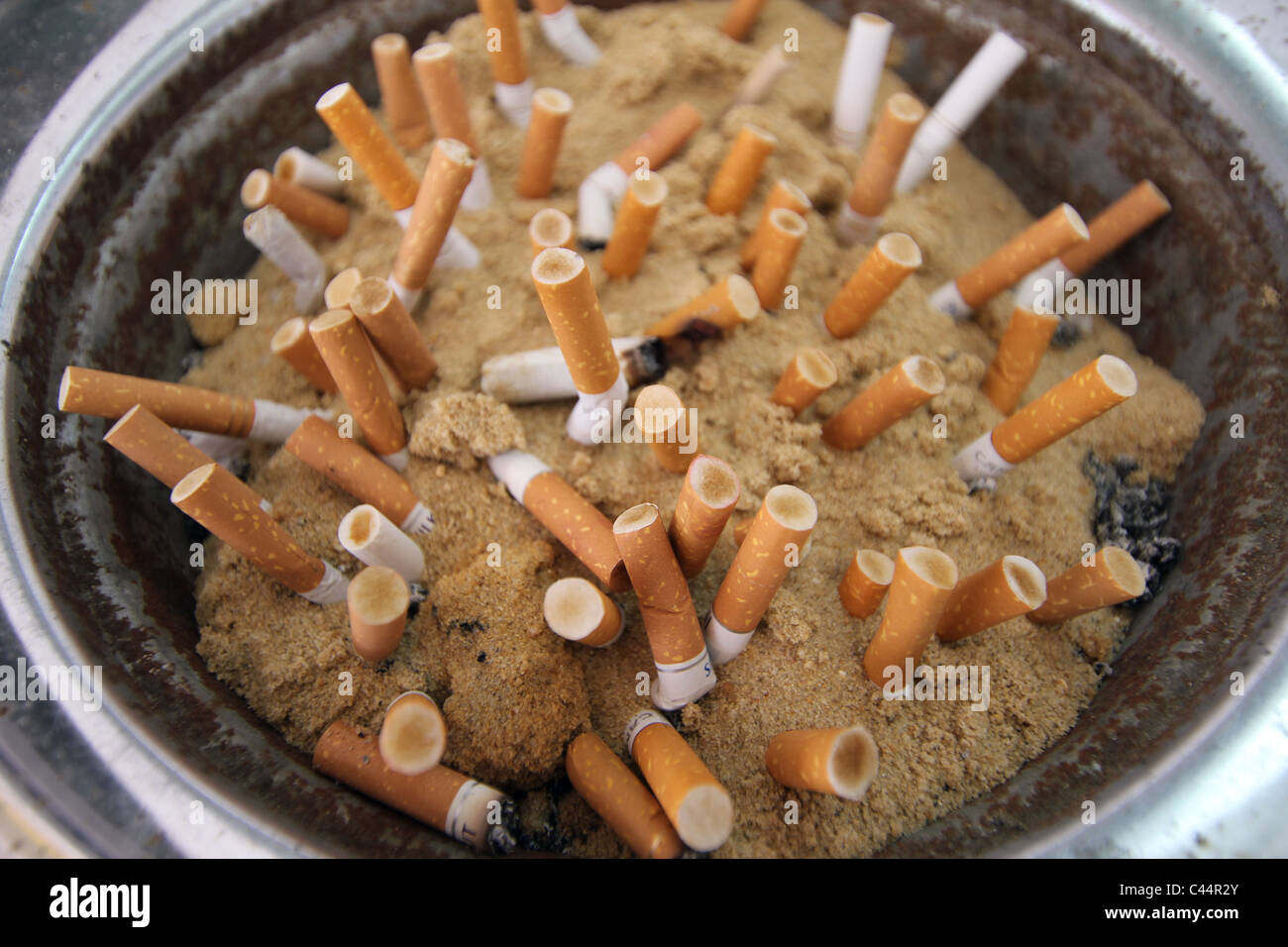 Cigarette butts stubbed out in a sand filled ash tray Stock Photo Alamy