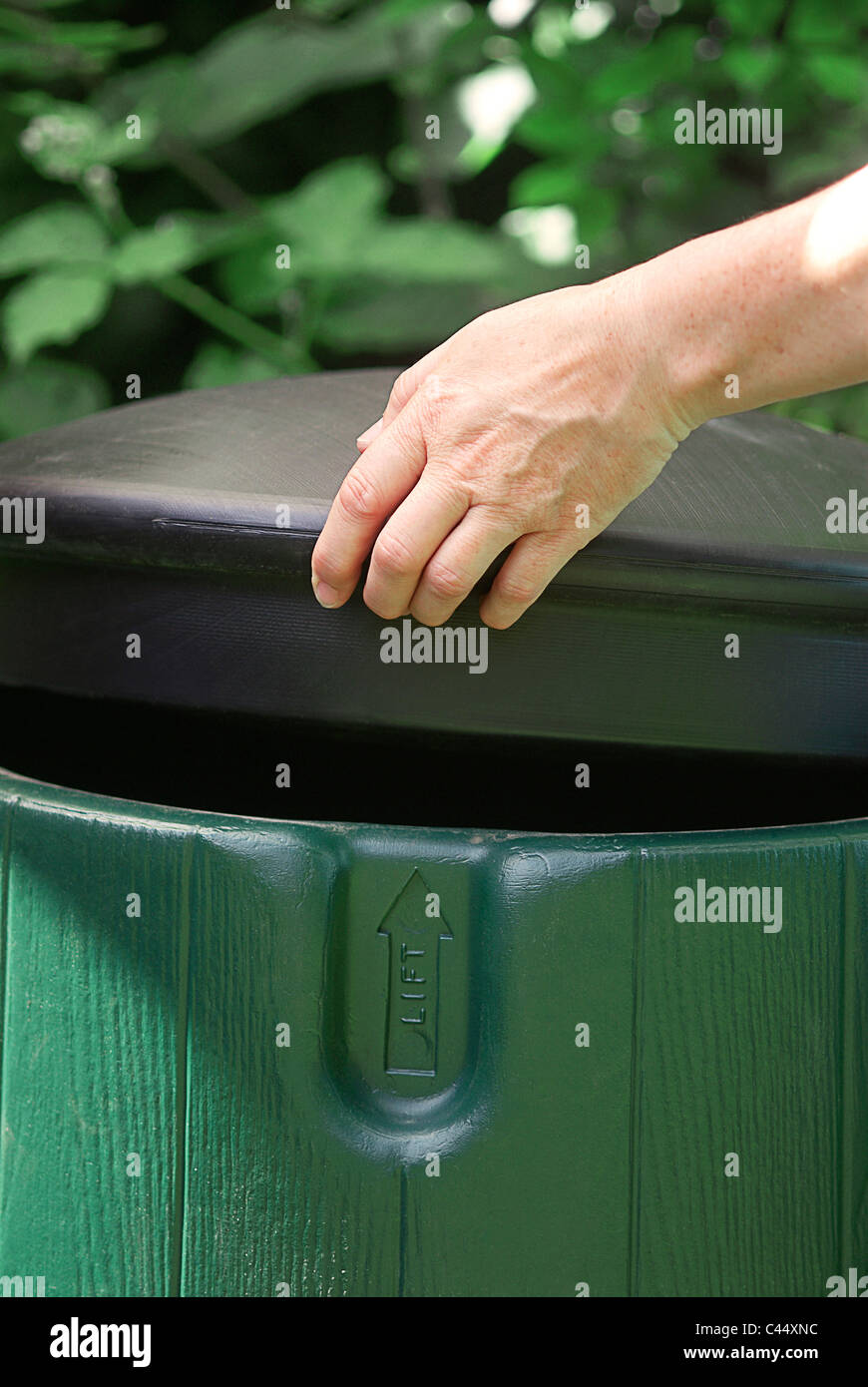 Womans hand taking lid off green plastic compost bin hires stock