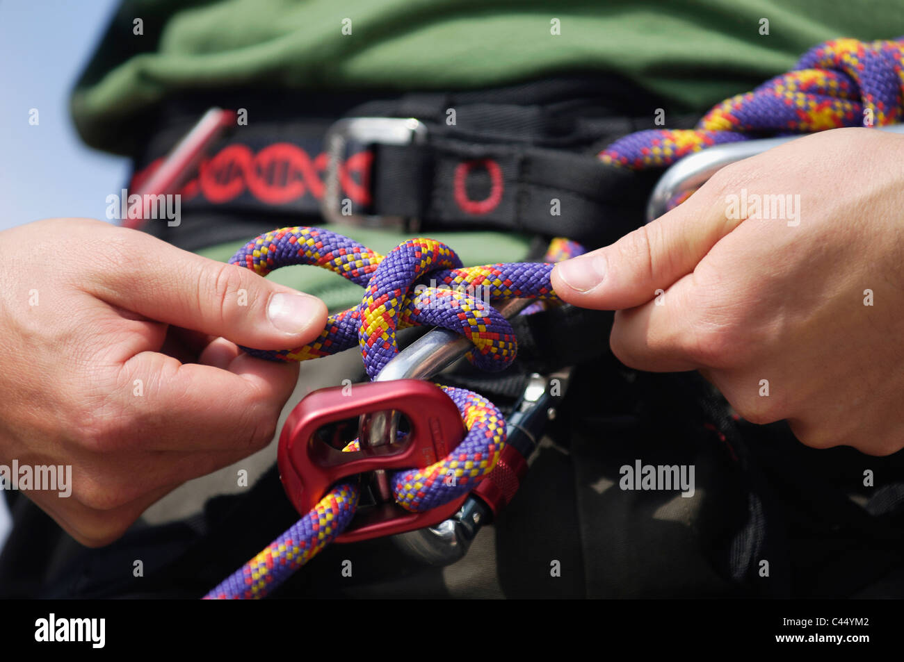 Man undoing hitch from gripping climbing rope hires stock photography