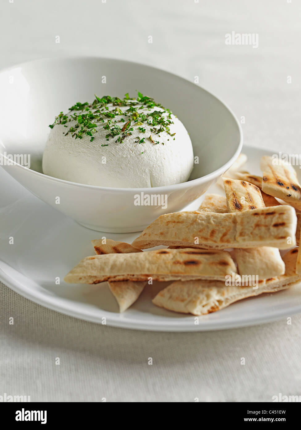 Bowl of cream cheese ball and pitta bread on plate, close-up Stock Photo