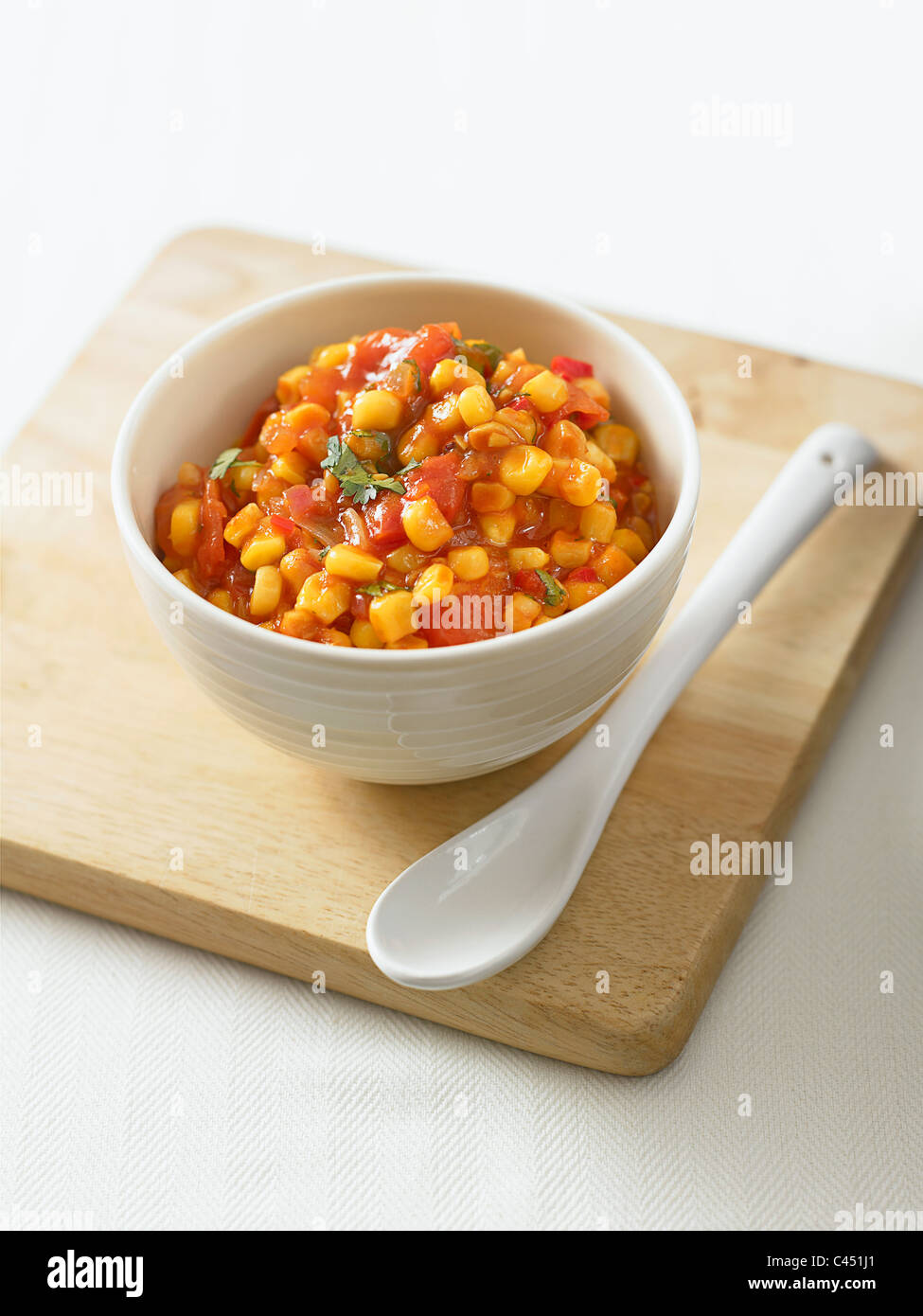 Bowl of corn relish on chopping board, close-up Stock Photo