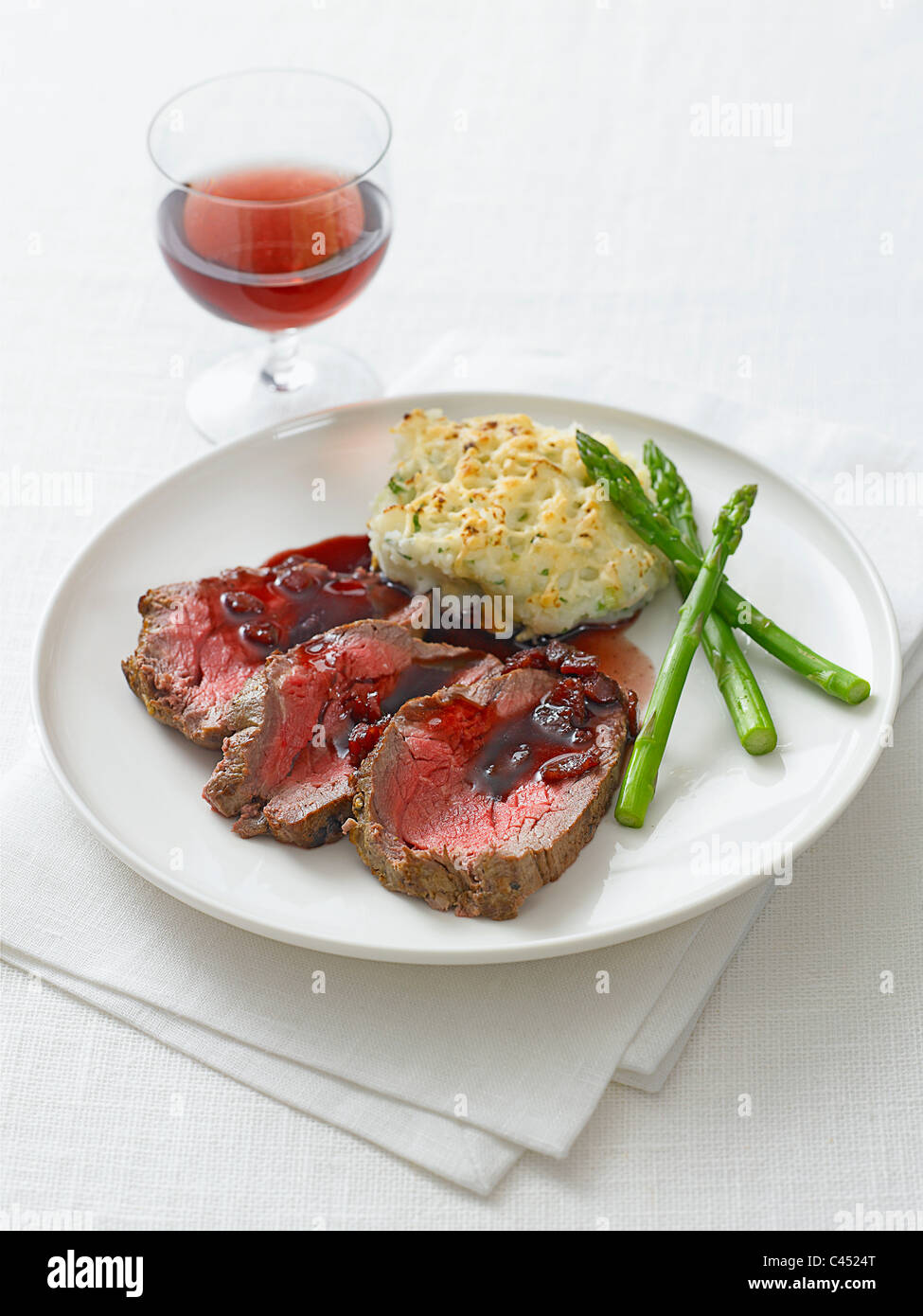 Filleted beef with redcurrant juice and vegetables on plate, close-up Stock Photo