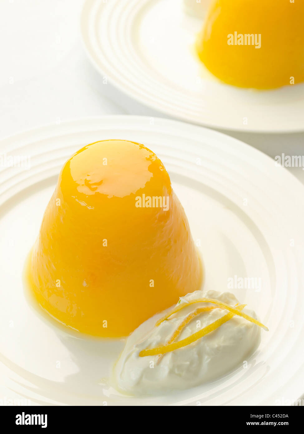 Orange jelly on white plate with dollop of Greek yoghurt Stock Photo