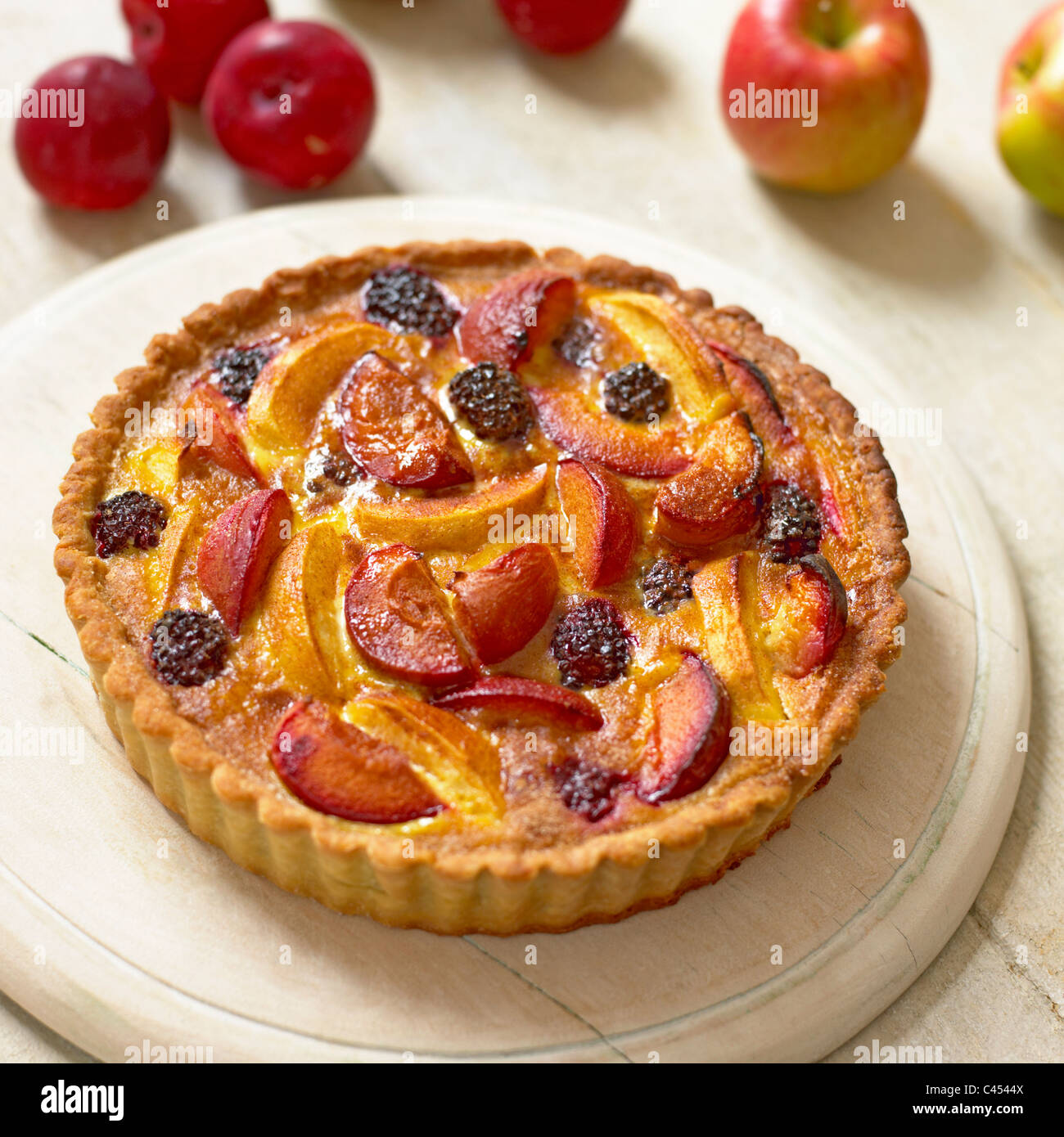 Apple and plum tart on chopping board, close-up Stock Photo