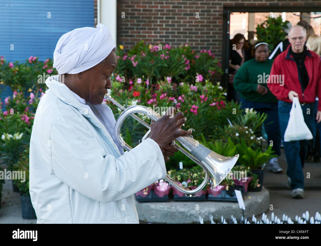 Detroit, Michigan - A woman plays the flugelhorn for tips as shoppers file by at Eastern Market, a farmers' market. Stock Photo