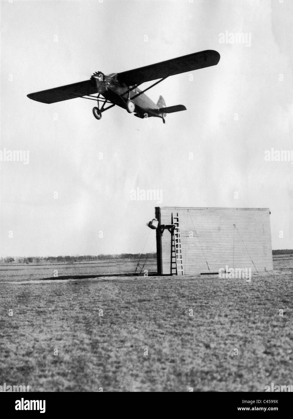 Mail plane takes on in-flight air mail, 1929 Stock Photo