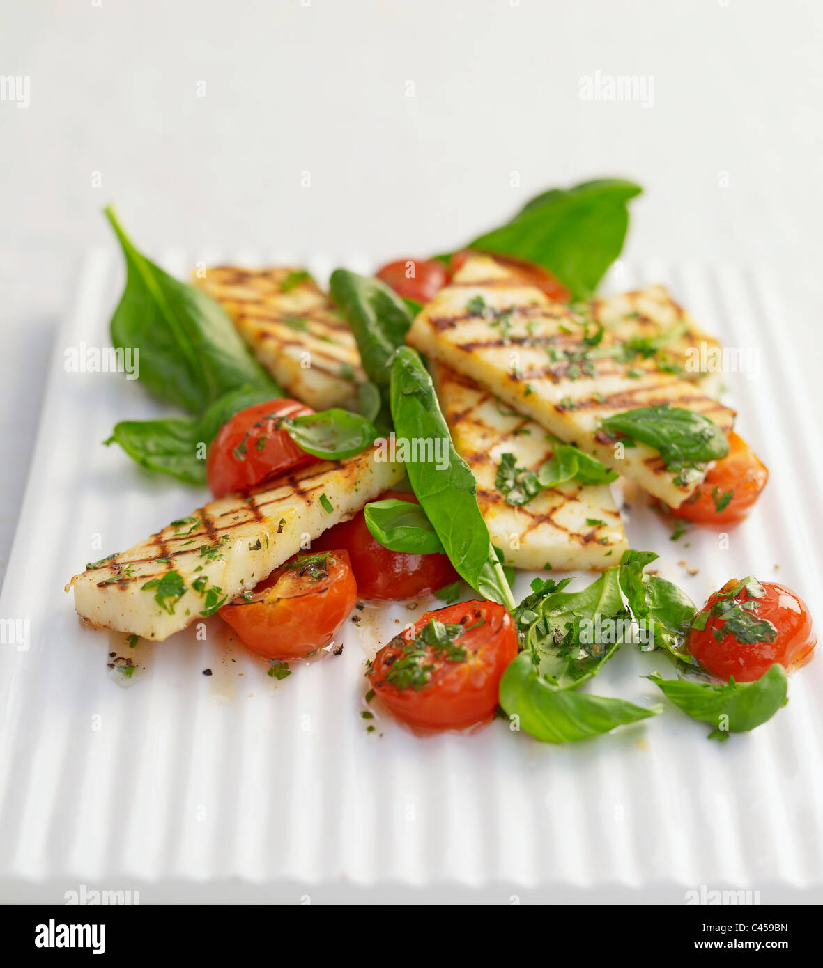 Grilled halloumi with roast tomatoes on plate, close-up Stock Photo