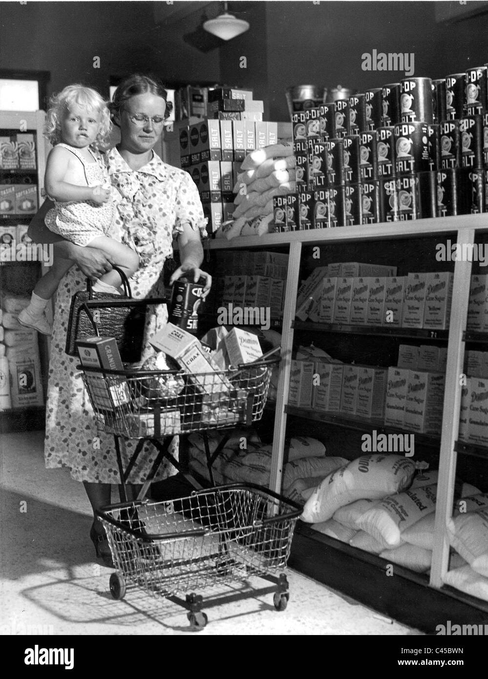 Women with a child and shopping trolley in an American supermarket, 1938 Stock Photo