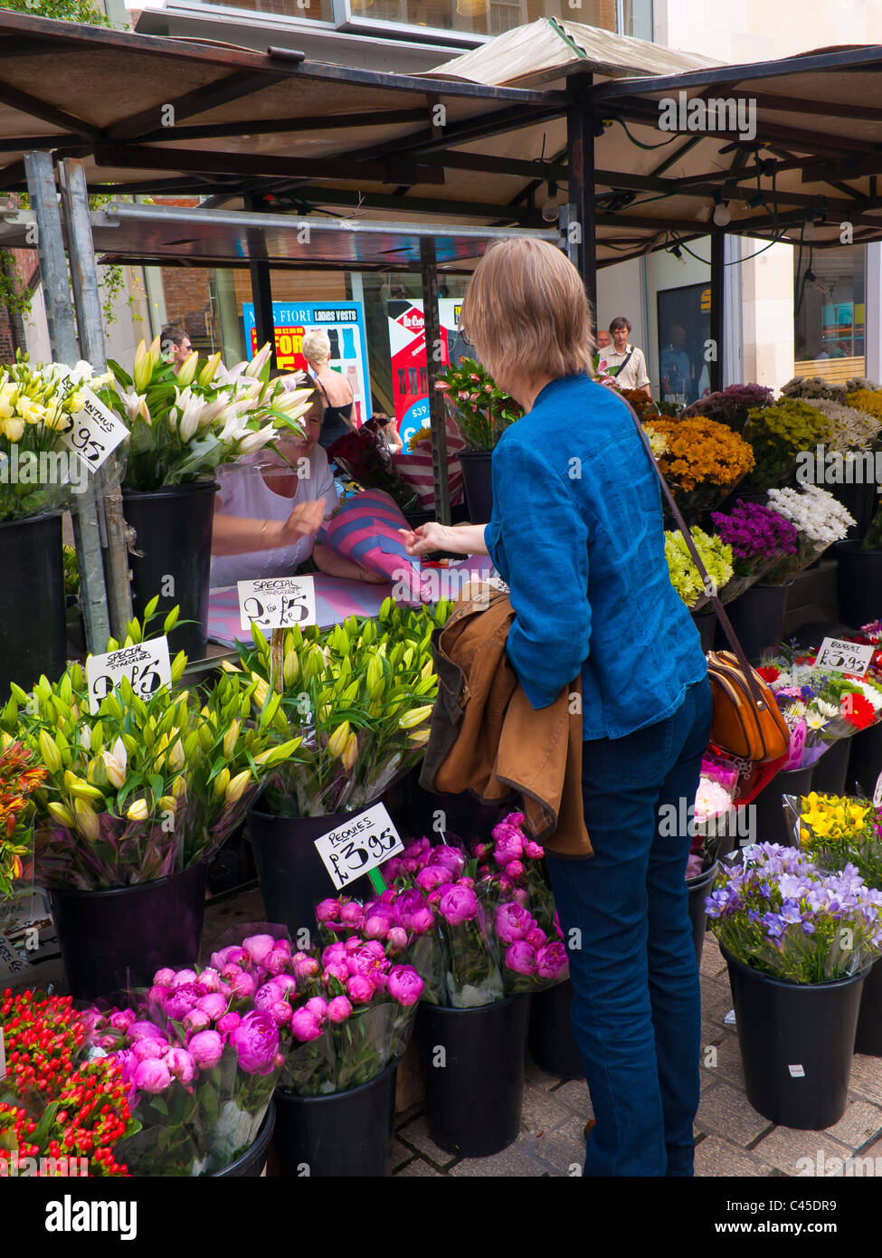 A woman buying flowers at a colourful stall in St Helen's Square in