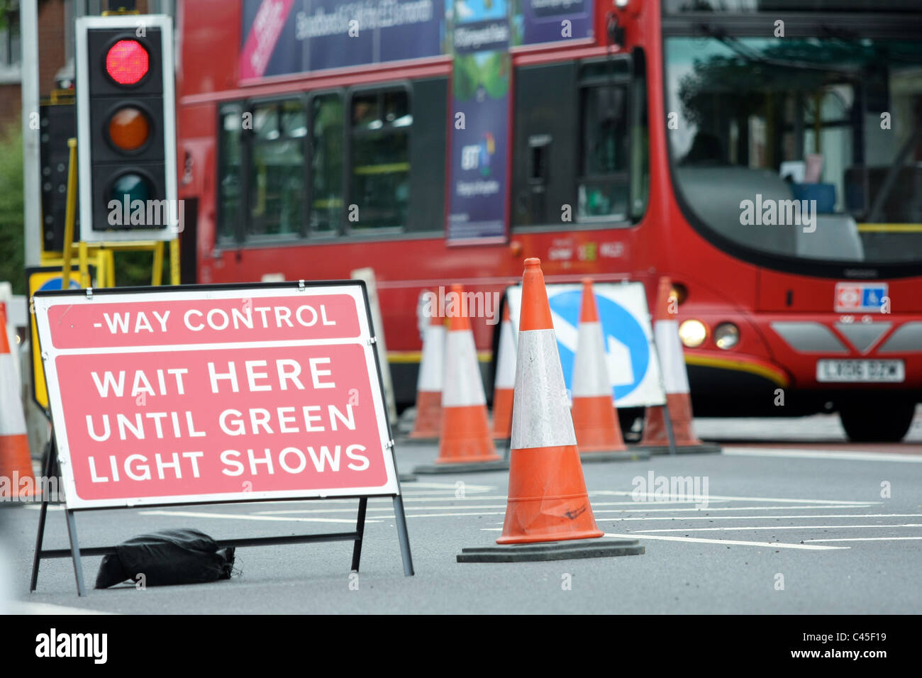 A bus traveling through roadworks controlled by a temporary set of traffic lights Stock Photo