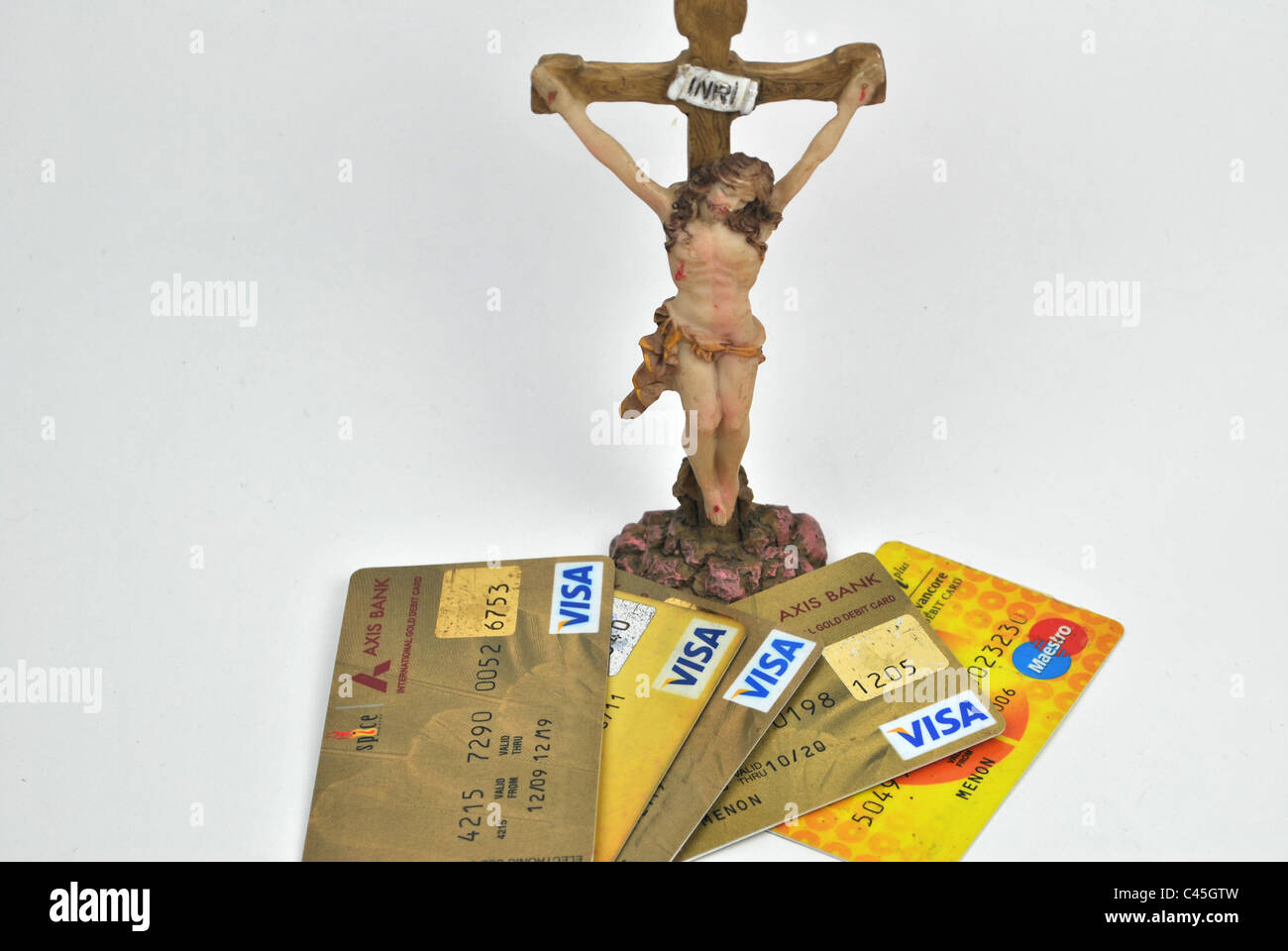 Credit cards scattered around a sculpture of jesus christ rip god crucifix cross jesus INRI  IESVS NAZARENVS REX IVDÆORVM Stock Photo