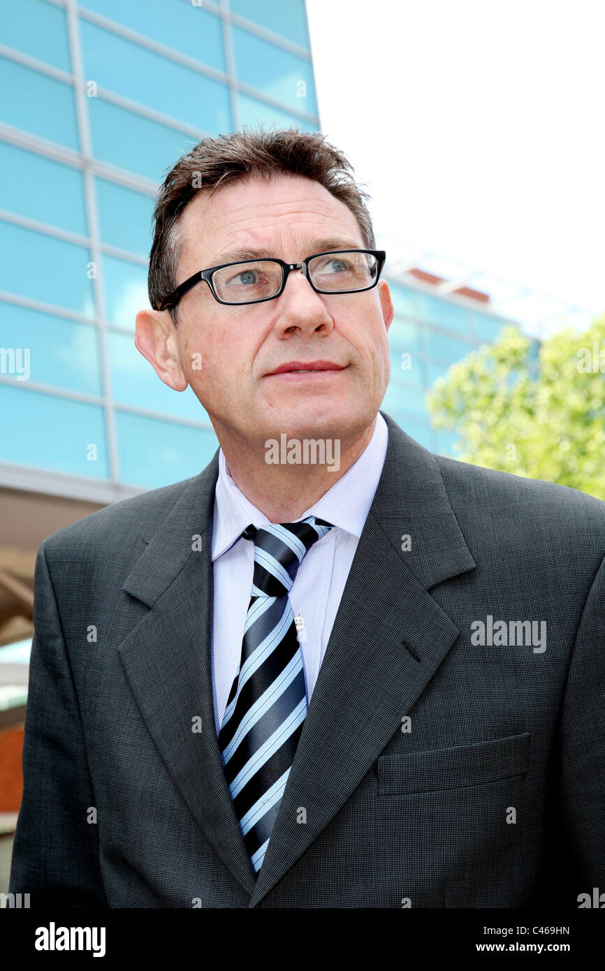 Businessman wearing specs outside a glass building. Stock Photo