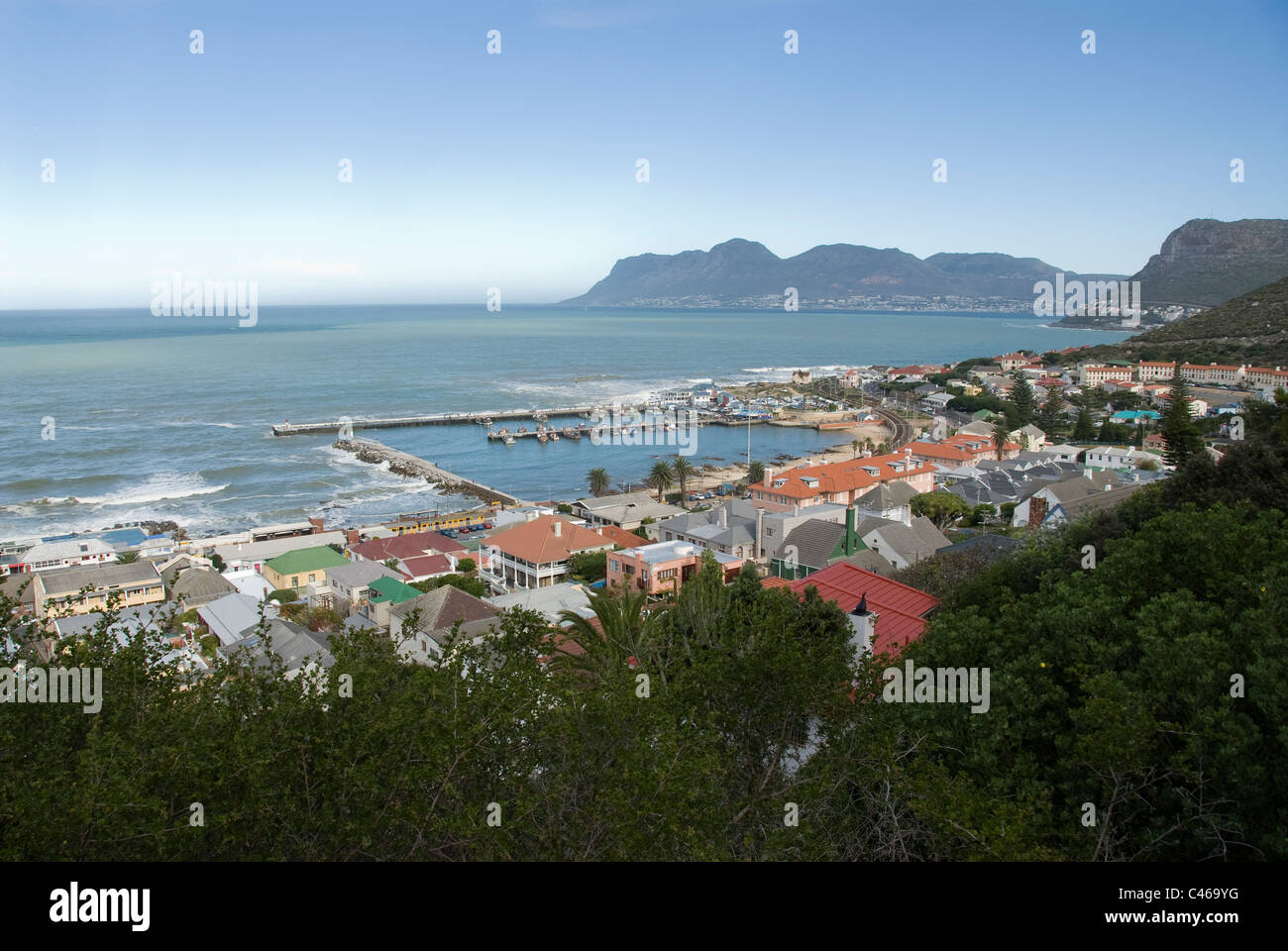 A view of Kalk Bay harbor and town with the Atlantic Ocean, Cape Point and Simon's Town in the distance. Stock Photo