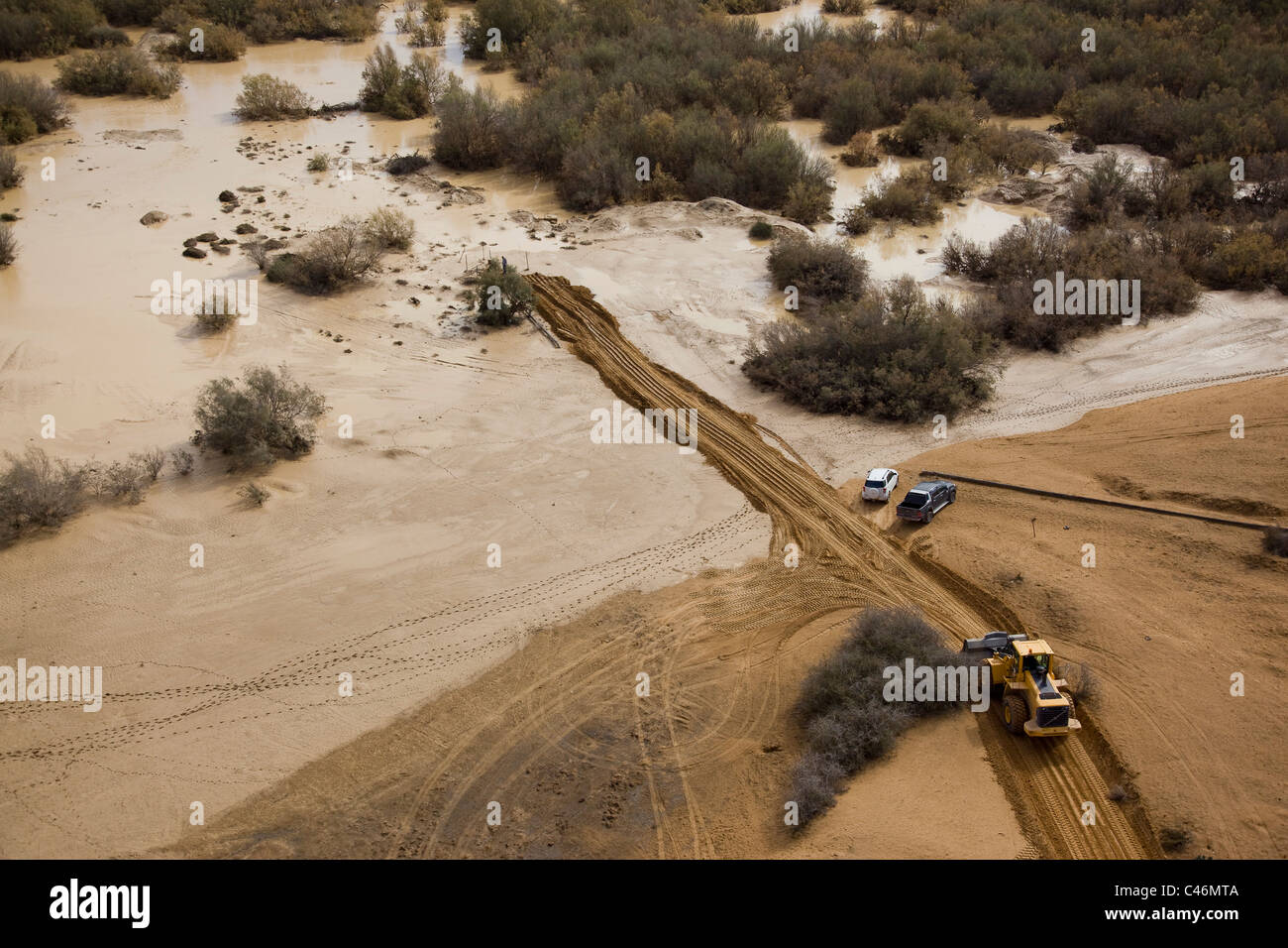 Aerial photograph of a tractor clearing a road in the Bsor stream after a flood in the Negev desert at winter Stock Photo