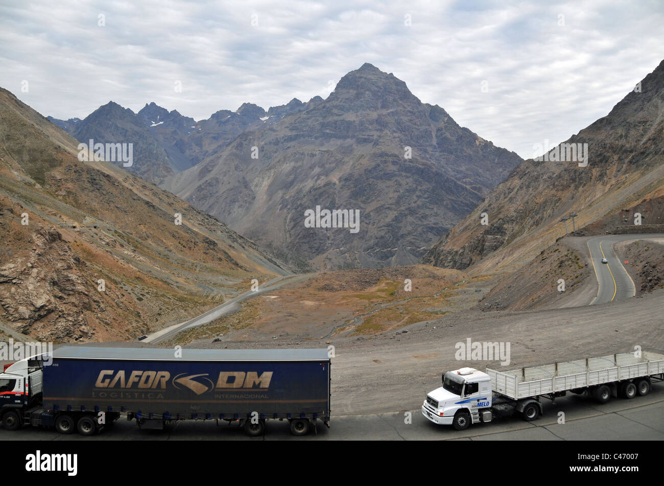 Mountain peak view two articulated lorries descending hairpin bend into Chile, summit Uspallata Pass, Ruta 7, Andes, Chile Stock Photo