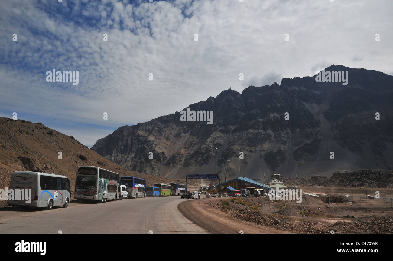 Blue sky white cloud Andean peak view Argentine buses cars queuing Chilean Border Post, Ruta 7, Uspallata Pass, Andes, Argentina Stock Photo