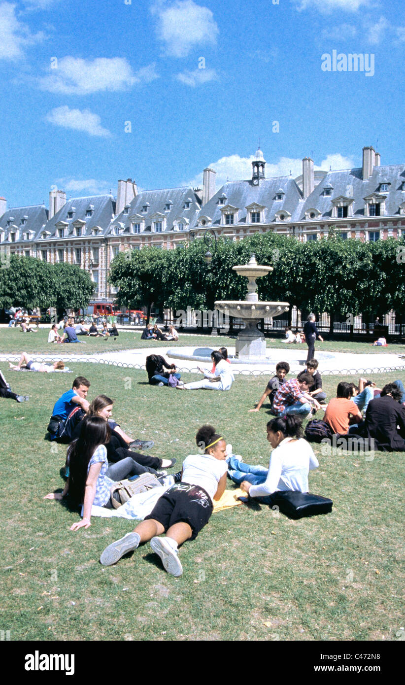 students  and other young people sitting and lying on the grass at park in Louis 1V place in Paris Stock Photo